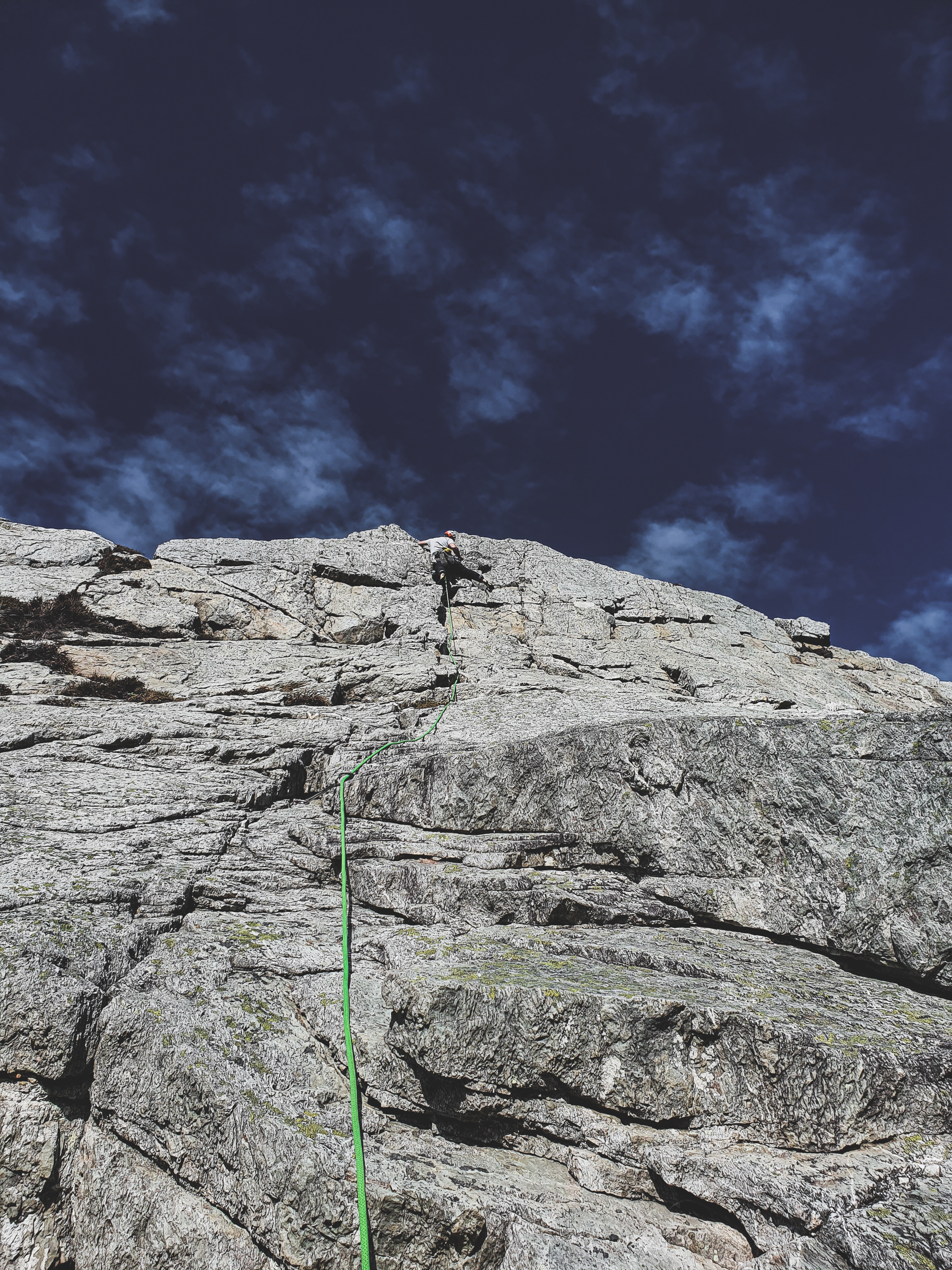 Climber photographed by the belayer at the top of a climb. Leading a trad route at Holyhead Mountain.