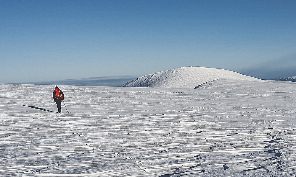 Guide walking in the snow on a mountain in Scotland
