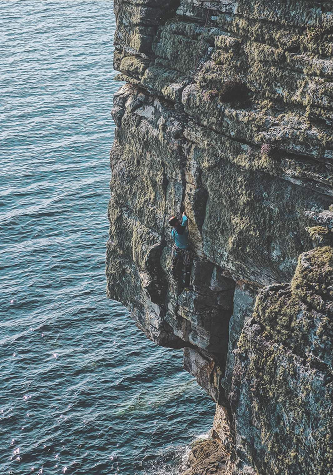 Man rock climbing on Elgol's sea cliffs in Skye, Scotland, with stunning coastal views.