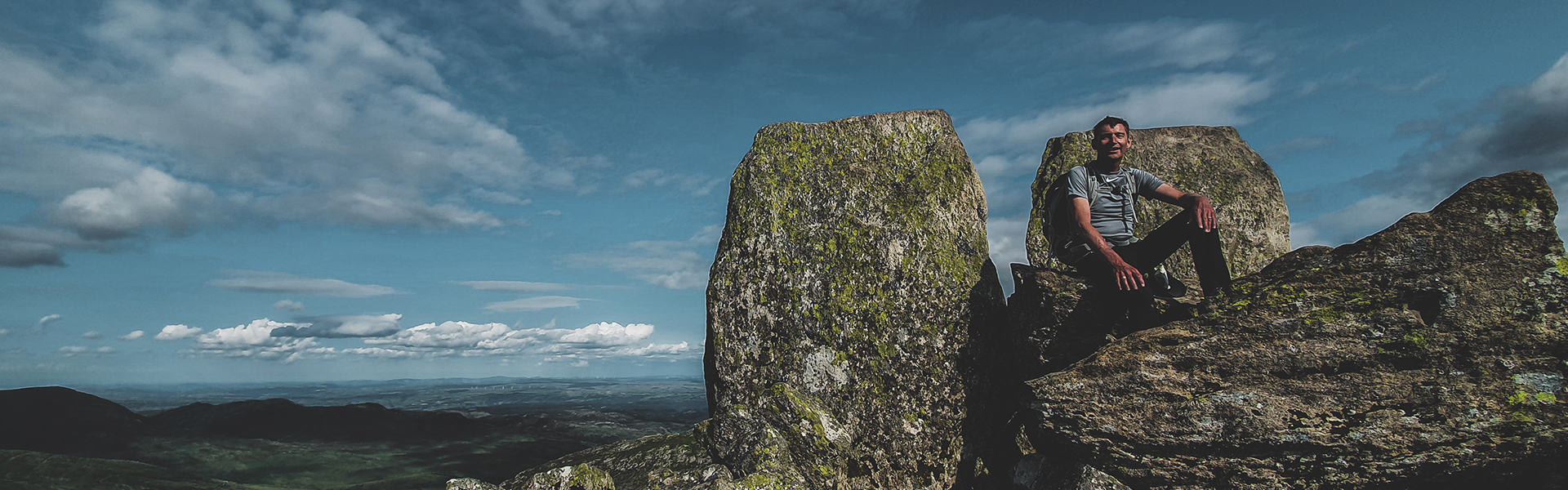 Man at the top of Tryfan, sitting on Adam and Eve