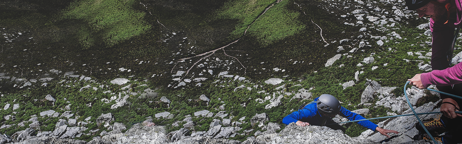 A climber getting belayed by his climbing partner, just about to top out at the top of Holyhead Mountain.